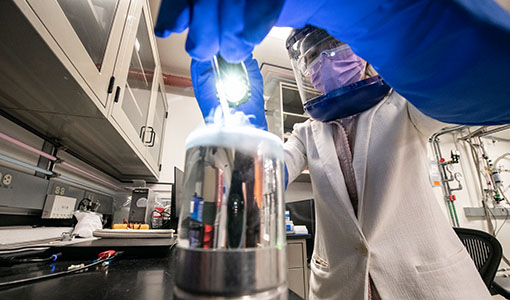 hp-fundamental-science-63695 One researcher with safety glasses and a face mask working on equipment in a lab.