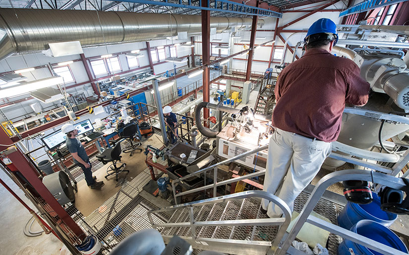 scale-up-piloting-research-52194 One researcher in a hard hat working on equipment in a lab.