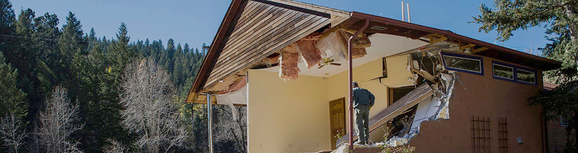 resilience-1-intergovernmental A person stands in the frame of a damaged home