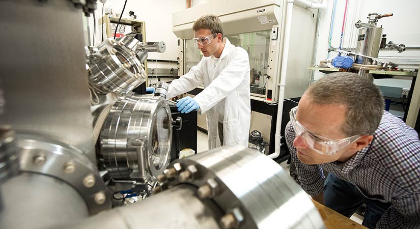 amo-31131 Four researchers stand in front of a large, black, cabinet-like computing device.