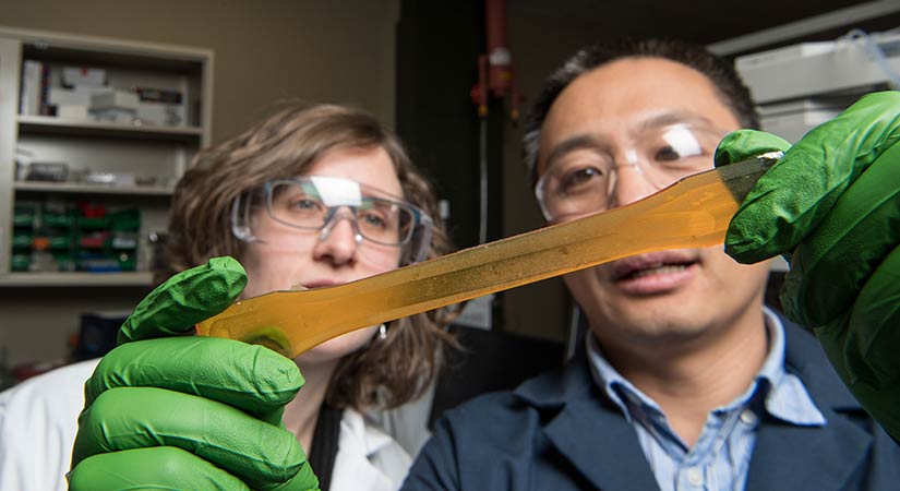resin-60853 A researcher holds a long, translucent, orange resin.