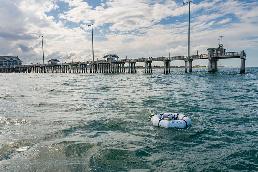20250515-updated-risk-management-framework-supports-success-of-marine-energy-devices-hero-wec-74202 A device floating in the ocean in front of a pier.