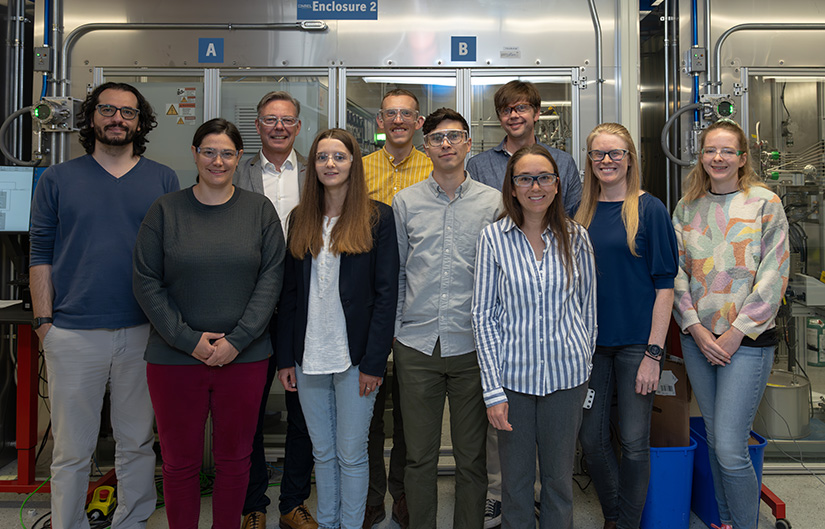 20250610-plastics-recycling-with-enzymes-takes-a-leap-forward-99618 Ten people stand in front of laboratory equipment.