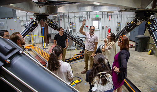 A photo of a group of people standing underneath large machinery.